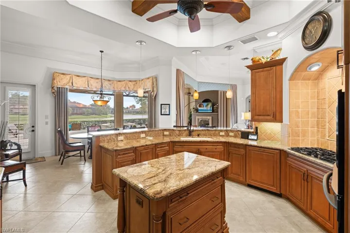 Kitchen with sink, pendant lighting, a center island, and light stone countertops