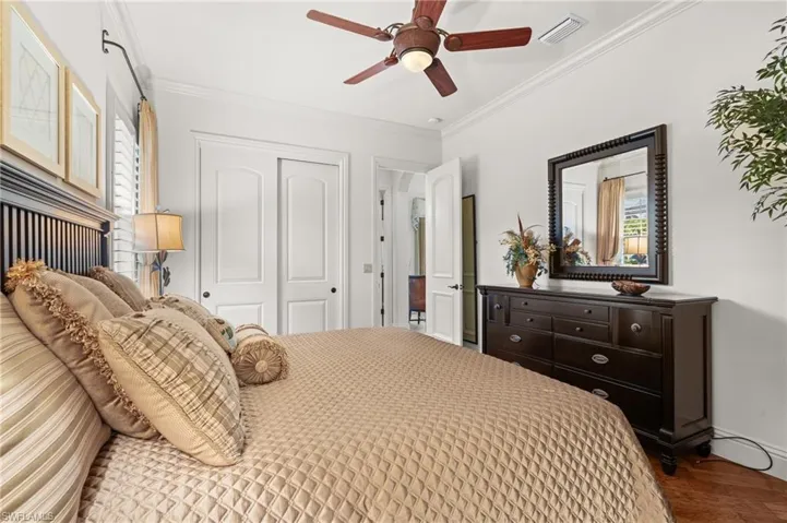 Bedroom with hardwood / wood-style flooring, ornamental molding, ceiling fan, and a closet