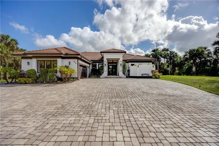 Mediterranean / spanish-style house with an attached garage, a tile roof, stucco siding, and decorative driveway