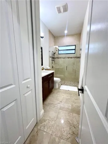 Full bathroom with a shower stall, vanity, light marble finish flooring, and a closet