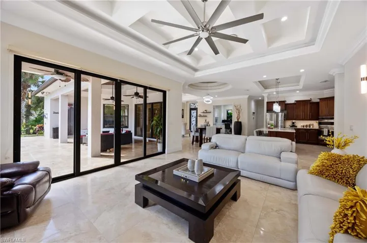 Living area featuring ornamental molding, a raised ceiling, coffered ceiling, ceiling fan, and recessed lighting