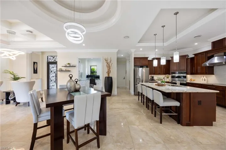 Dining room with crown molding, a chandelier, a raised ceiling, and recessed lighting