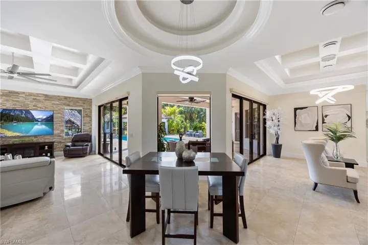 Dining area featuring coffered ceiling, french doors, beam ceiling, an accent wall, and a ceiling fan