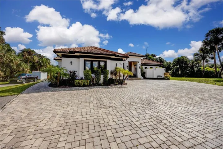 Mediterranean / spanish-style house featuring decorative driveway, stucco siding, and a tiled roof