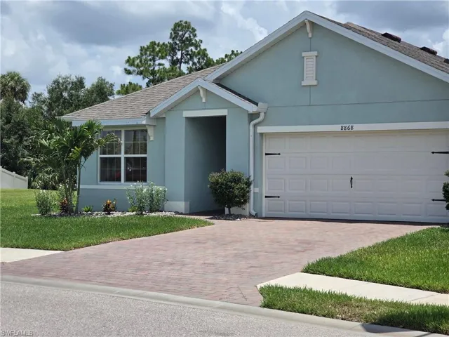 Ranch-style house with stucco siding, decorative driveway, an attached garage, and a front yard