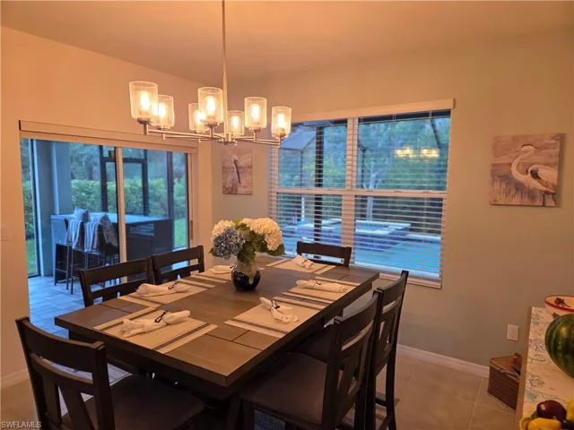 Tiled dining room featuring a chandelier and lofted ceiling
