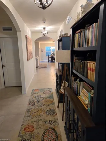 Corridor with arched walkways and light tile patterned flooring