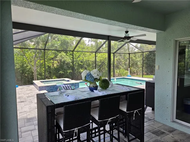 View of patio featuring a ceiling fan, a pool with connected hot tub, and a lanai