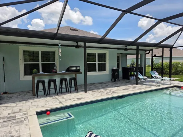Outdoor pool with a patio area, ceiling fan, and a lanai