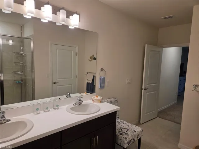 Bathroom with double vanity, a shower stall, and tile patterned floors