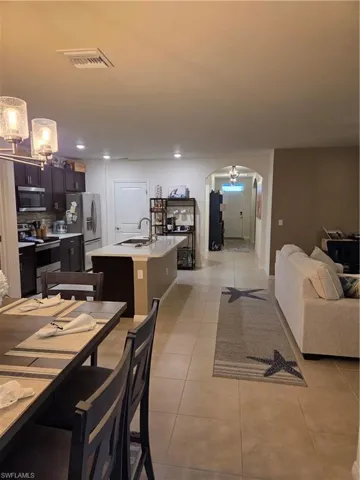 Dining area with arched walkways, light tile patterned floors, a chandelier, and recessed lighting