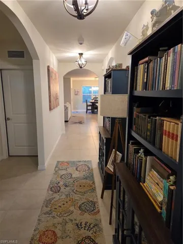 Hall with arched walkways, light tile patterned flooring, and a chandelier