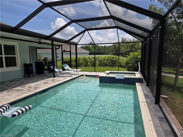 View of swimming pool featuring a patio area, a pool with connected hot tub, a ceiling fan, and a lanai