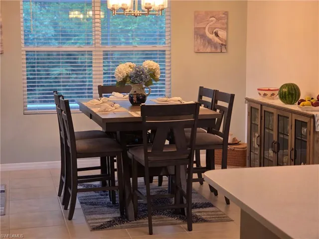Tiled dining room featuring a chandelier and baseboards