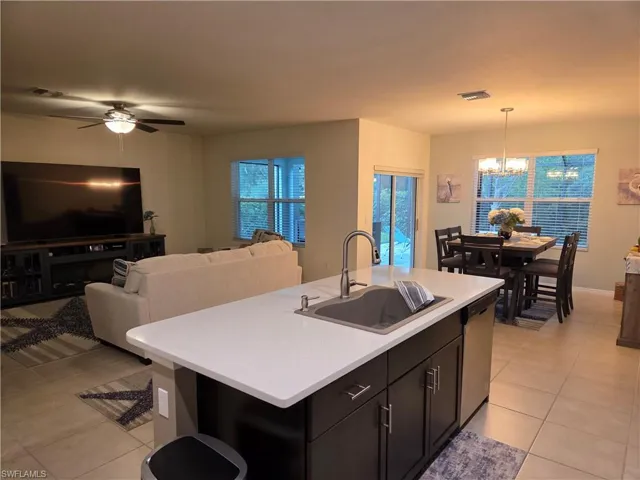 Kitchen with dishwasher, a chandelier, light tile patterned floors, light countertops, and open floor plan