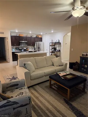 Living room with arched walkways, recessed lighting, and a ceiling fan