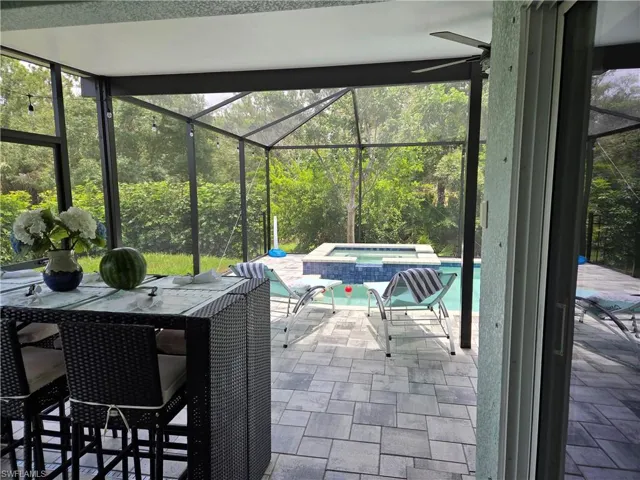 View of patio / terrace with a pool with connected hot tub and glass enclosure