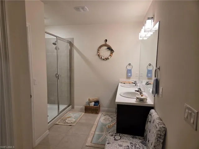 Bathroom with double vanity, a stall shower, and tile patterned floors