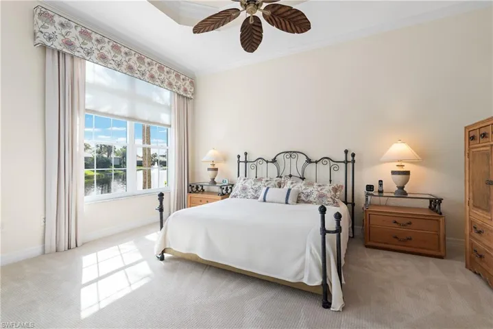 Bedroom with light colored carpet, ornamental molding, and a ceiling fan
