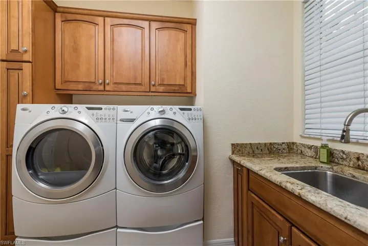 Washroom featuring a textured wall, cabinet space, and washing machine and clothes dryer