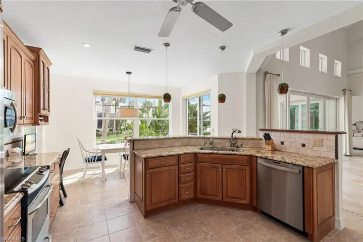 Kitchen featuring brown cabinetry, backsplash, stainless steel appliances, pendant lighting, and recessed lighting