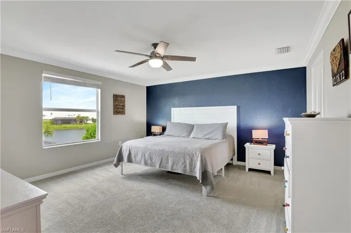 Bedroom featuring ceiling fan, ornamental molding, and light colored carpet