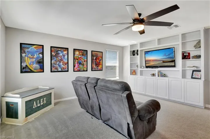 Living room with light carpet, built in features, and ceiling fan