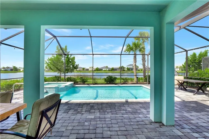 View of swimming pool with an in ground hot tub, a water view, a patio area, and a lanai