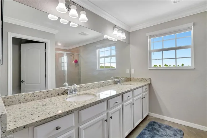 Bathroom featuring tile patterned floors, double vanity, a shower with shower door, and ornamental molding