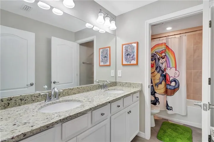 Full bathroom featuring dual vanity, tile patterned flooring, toilet, and shower / bath combination with curtain