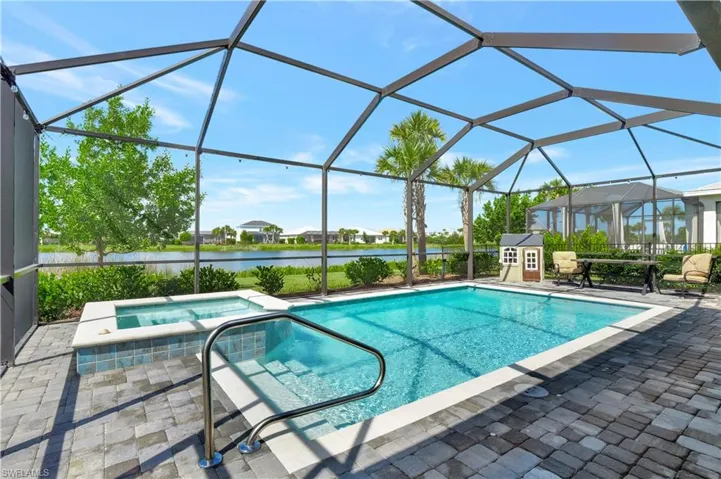 View of pool with an in ground hot tub, a patio, glass enclosure, and a water view