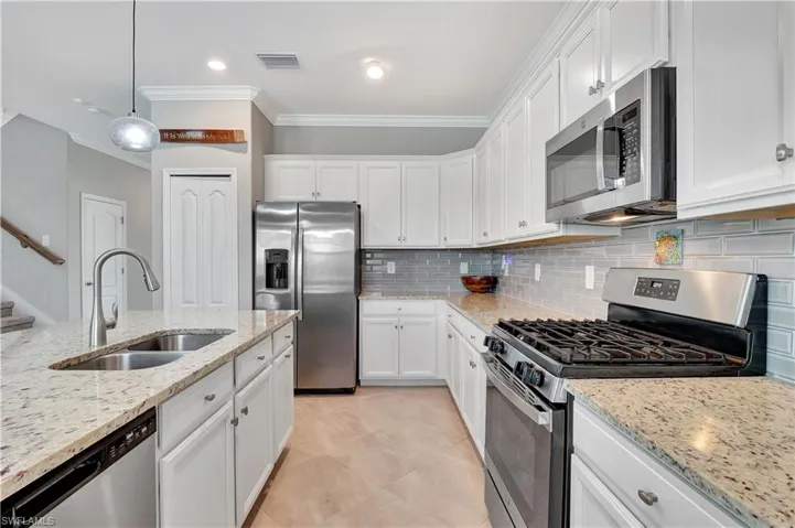 Kitchen featuring appliances with stainless steel finishes, tasteful backsplash, sink, light tile patterned floors, and ornamental molding