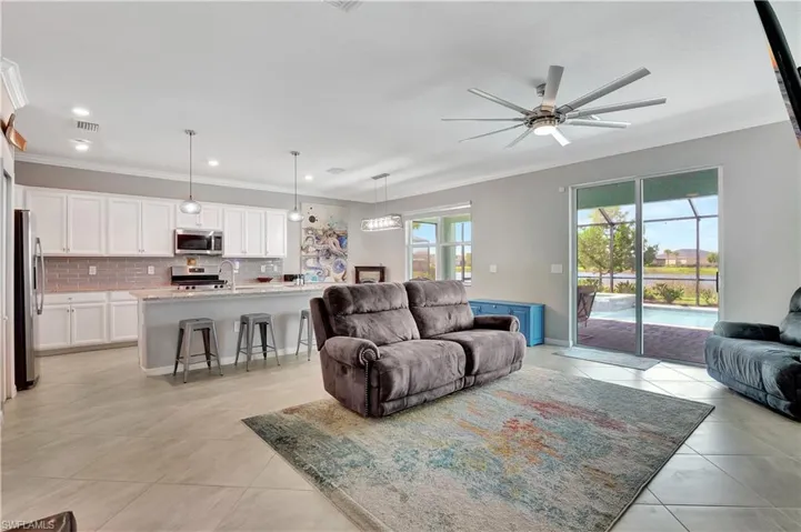 Living room with ornamental molding, light tile patterned floors, and ceiling fan
