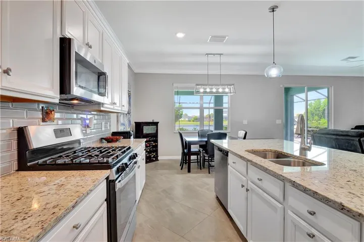 Kitchen featuring light tile patterned floors, a wealth of natural light, tasteful backsplash, and stainless steel appliances