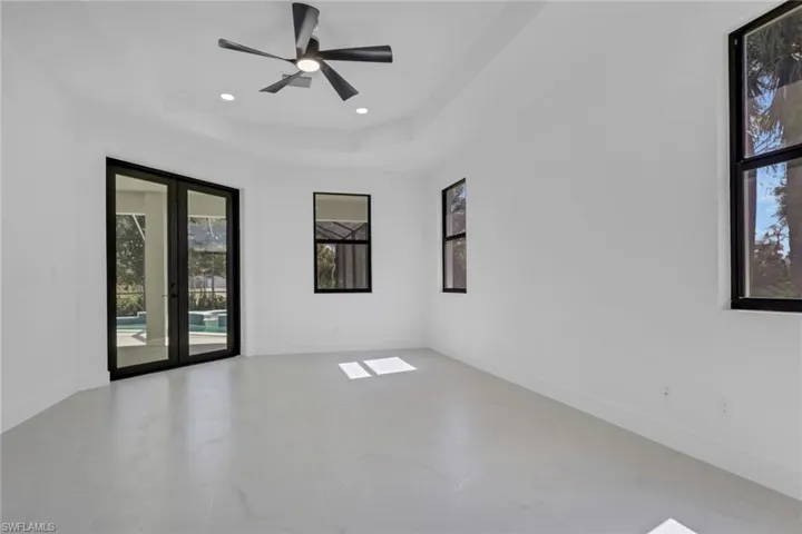 Unfurnished room with french doors, a ceiling fan, a raised ceiling, and recessed lighting