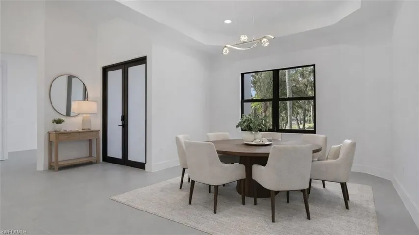 Virtually Staged Dining area featuring a raised ceiling, french doors, a chandelier, and concrete flooring