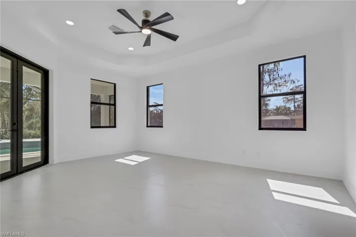 Empty room with a ceiling fan, a tray ceiling, recessed lighting, and finished concrete flooring