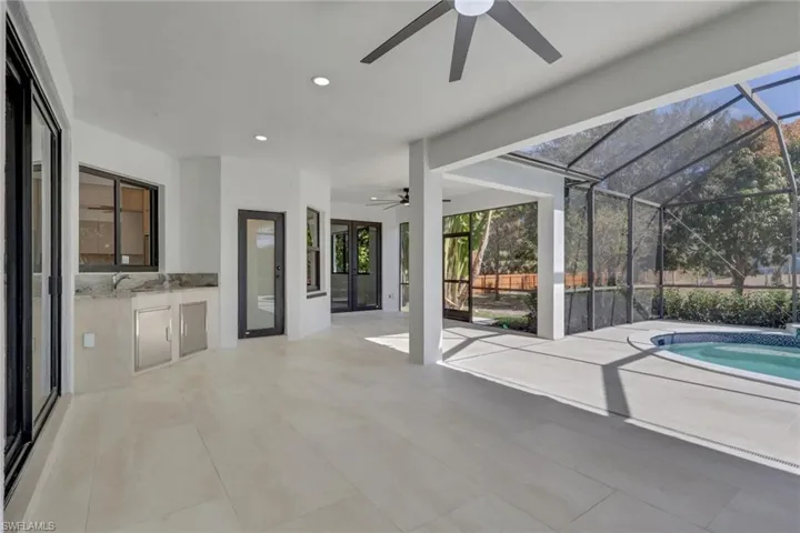 View of patio / terrace with ceiling fan, a lanai, a sunroom, an outdoor kitchen, and french doors