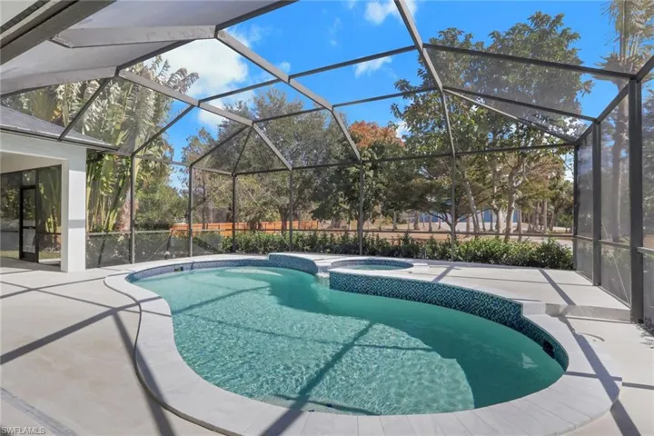 Integrated pool / hot tub with a sunroom, glass enclosure, and a patio area