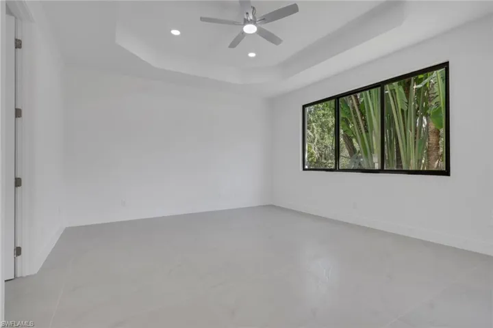 Empty room featuring a tray ceiling, ceiling fan, and a chandelier