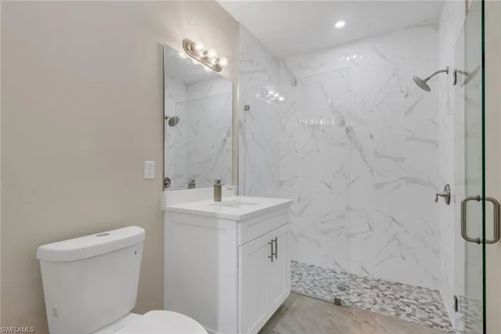 Bathroom featuring vanity and a marble finish shower