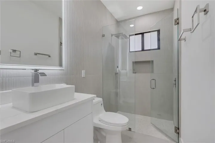 Full bath with double vanity, a soaking tub, tile walls, and light marble finish flooring