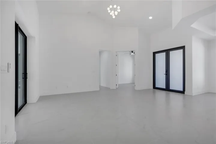 Unfurnished room with french doors, a high ceiling, a ceiling fan, and hanging lights