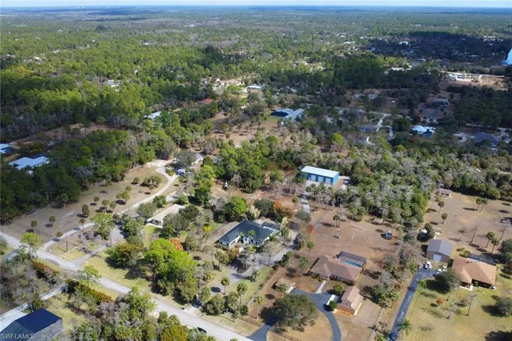 Aerial overview of property's location with a heavily wooded area and nearby suburban area
