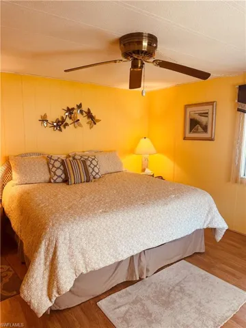 Bedroom with wood finished floors, ceiling fan, a textured ceiling, and wooden walls