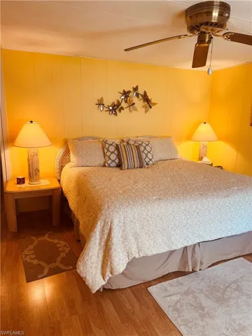 Bedroom with wood finished floors, a ceiling fan, and wooden walls