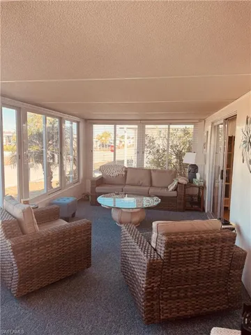 Sunroom / solarium featuring a textured ceiling and carpet floors