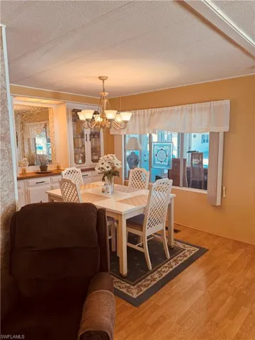 Dining space with a chandelier, a textured ceiling, and wood finished floors