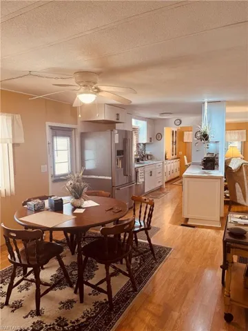 Dining space with light wood-type flooring, a textured ceiling, and ceiling fan