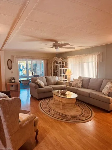 Living room featuring ceiling fan, wood finished floors, and a textured ceiling